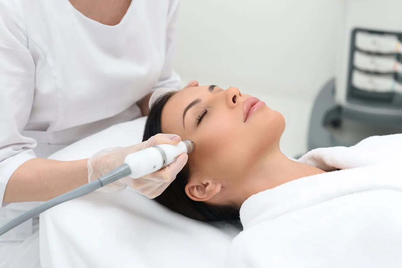 An esthetician performing a facial skin treatment with a handheld device on a client at a med spa