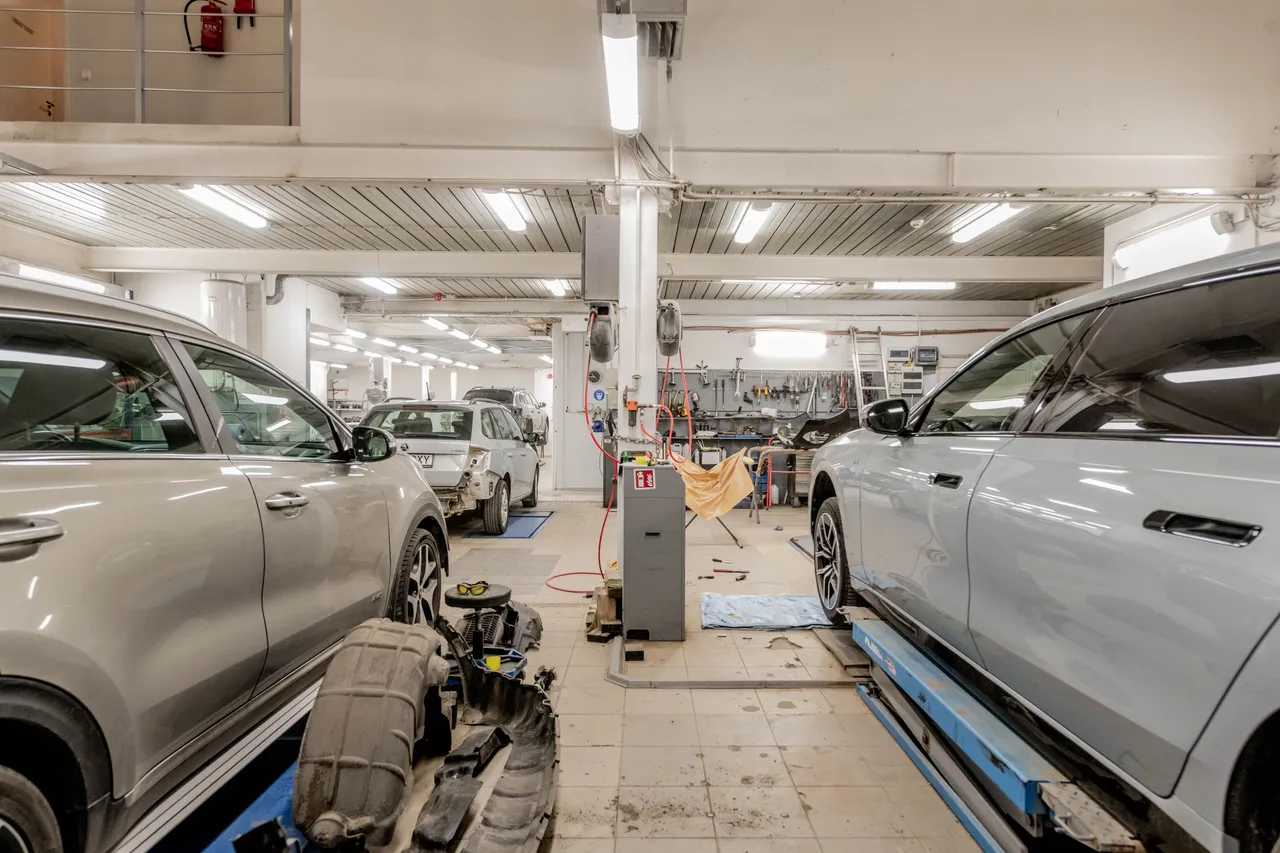 Wide interior view of a modern automotive repair shop with several cars undergoing maintenance