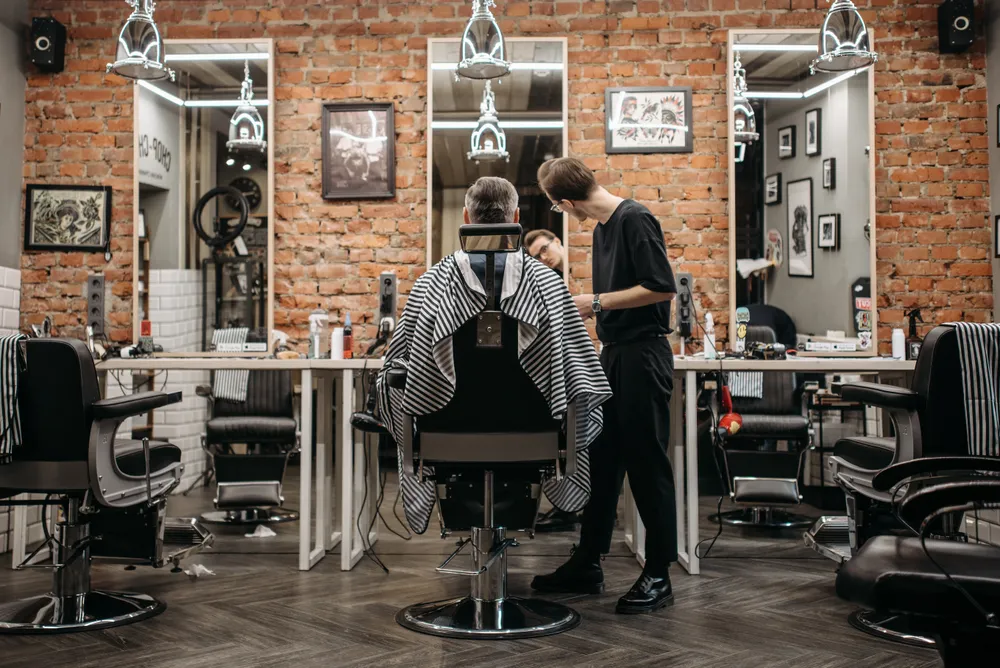 A skilled barber attending to a client in a stylish barbershop with exposed brick walls