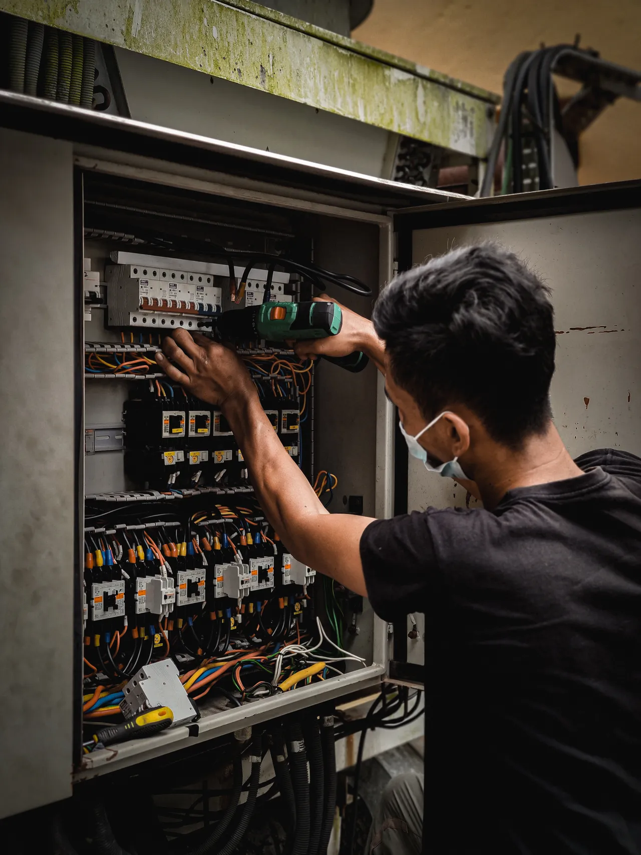 An electrician adjusting wiring inside an electrical circuit breaker panel