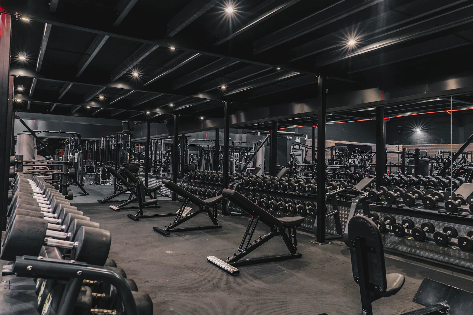 A large gym floor lined with dumbbell racks and weight benches