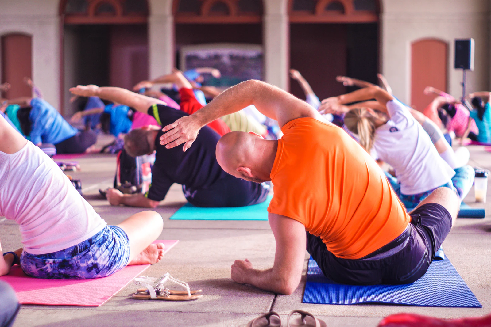 A group fitness class stretching on colorful mats in a bright studio