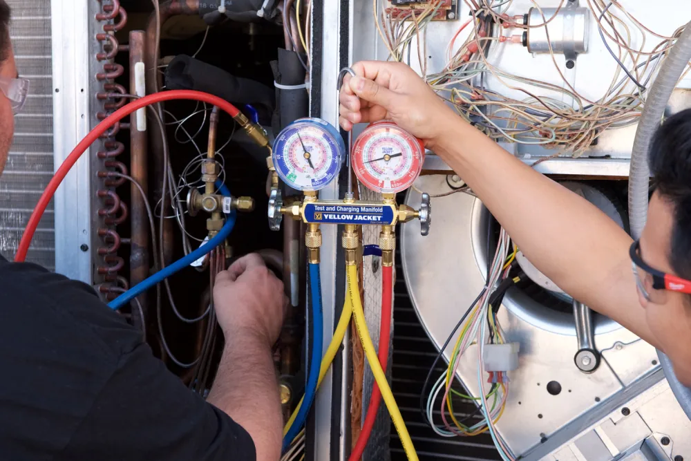 An HVAC technician using a manifold gauge set to charge and service an air conditioning system