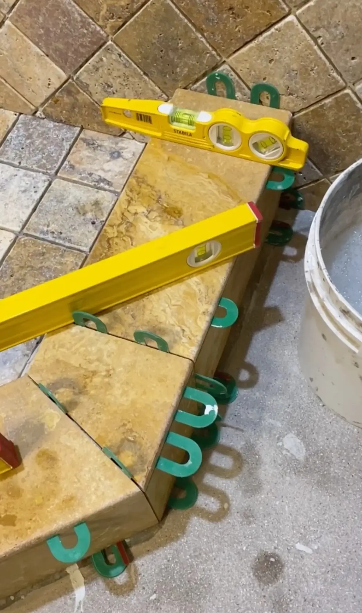 Tile installer measuring and setting floor tile on the job